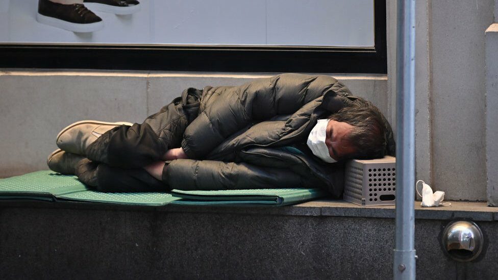 A homeless man sleeps on the pavement in the city of Daegu