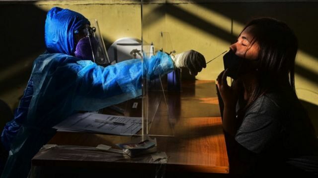 A health worker collects a swab sample from a passenger to test for the Covid-19 coronavirus, at a train station in Quezon City, suburban Manila on January 18, 2022.